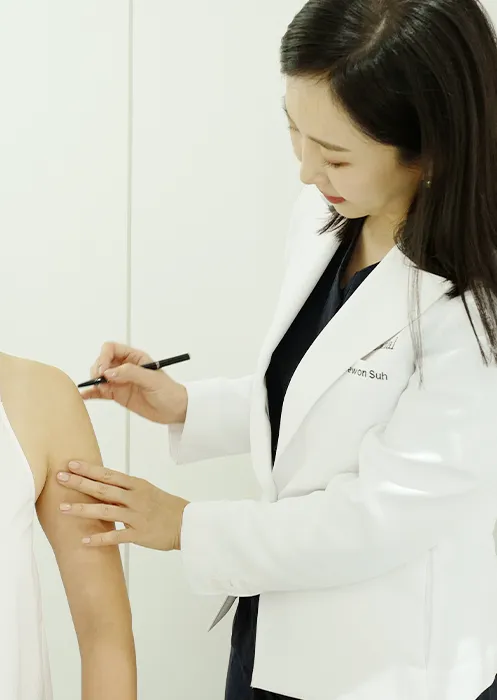 환자의 팔에 시술 부위를 표시하는 의료진